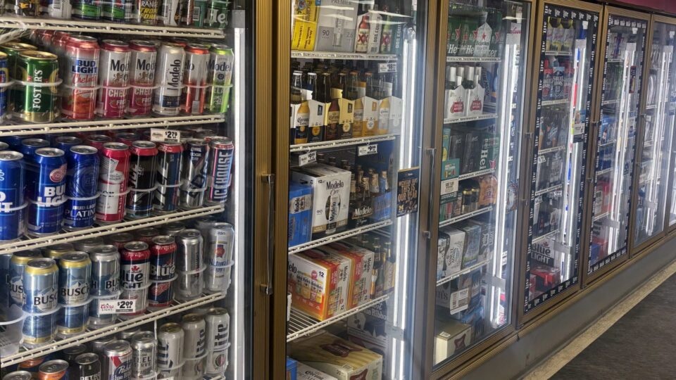 Fully stocked beer coolers in a store.