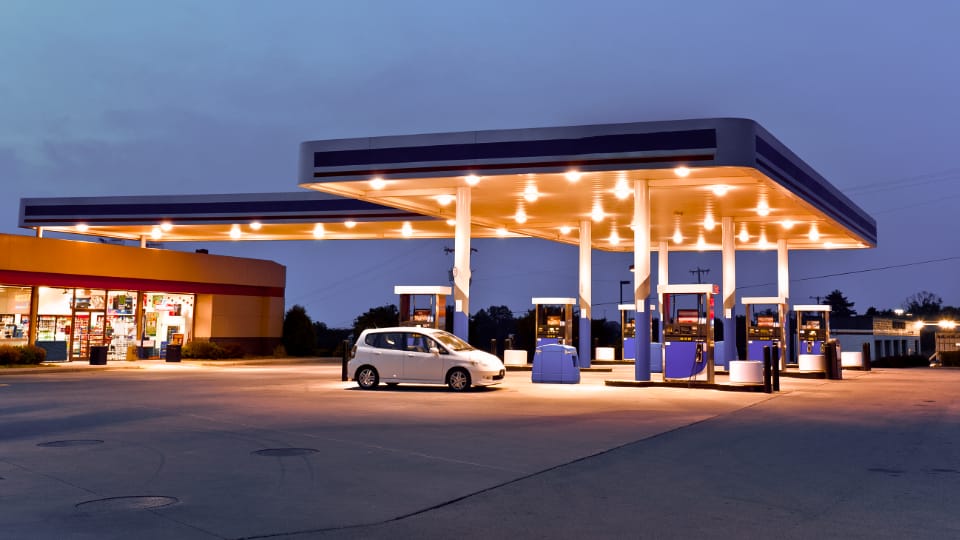 Self serve gas station at dusk with one car filling up.